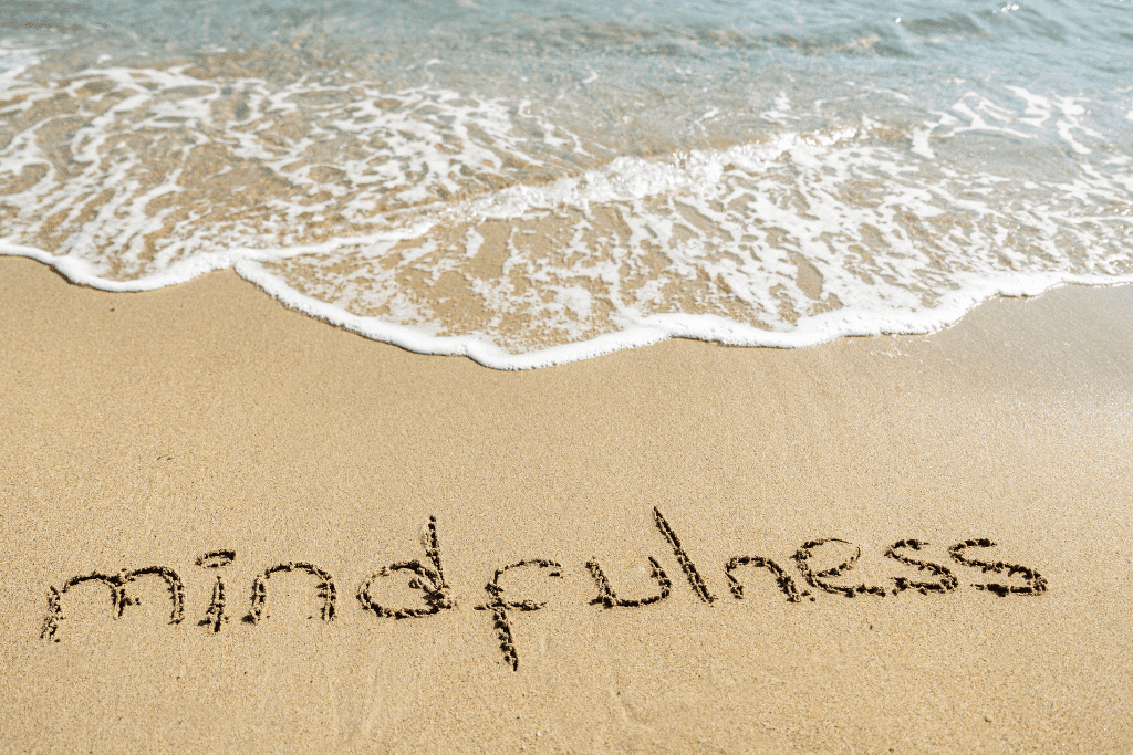 Mindfulness written in the sand of a beach